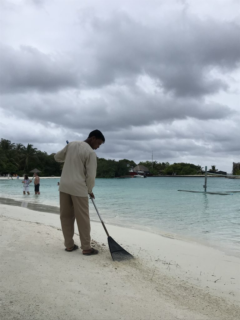 Man sweeping the perfect white sand