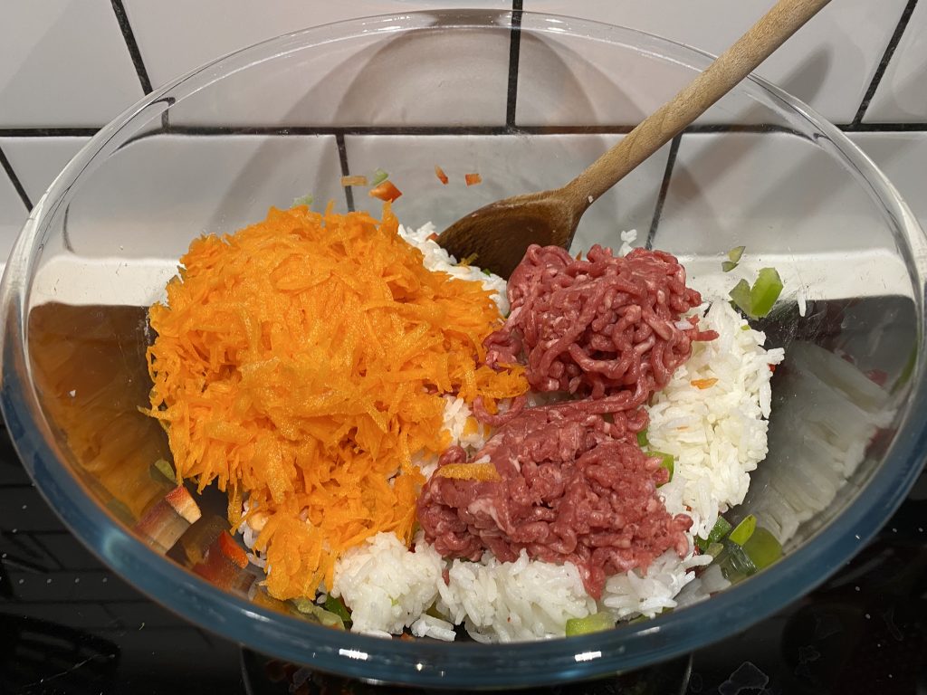 Mixing in the grated carrot and minced beef