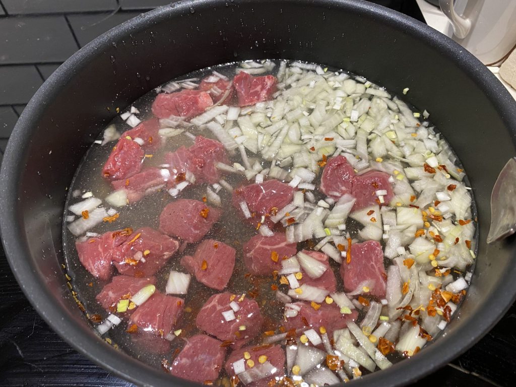 Cooking the beef and onions for the Okra sauce