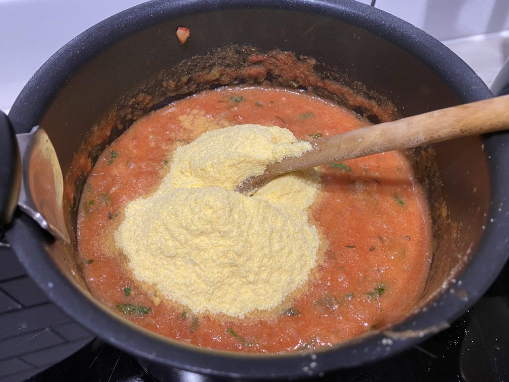 Adding cornmeal to the tomato mixture