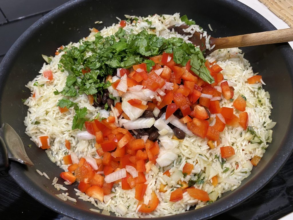 Sauté the cooked rice with beans and remaining vegetables