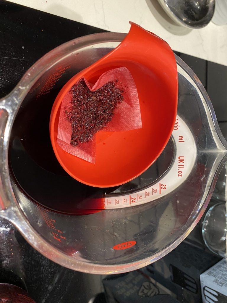Straining the hibiscus flowers from the liquid