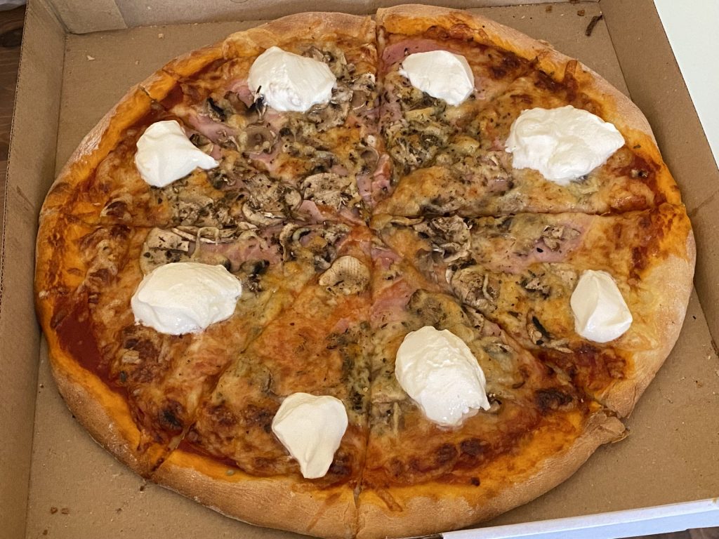 Pizza from pizzeria Fantasy with mushrooms, ham and soured cream