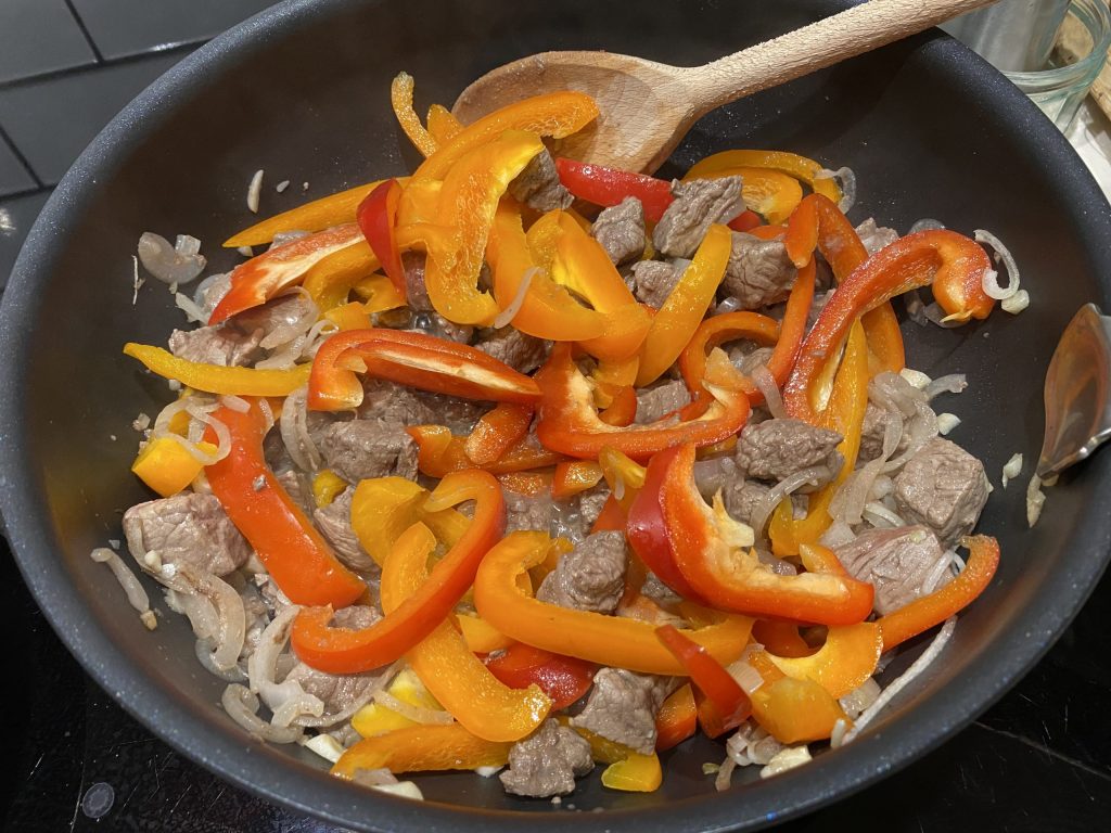 Frying the beef, onion, garlic and peppers for the laghman sauce